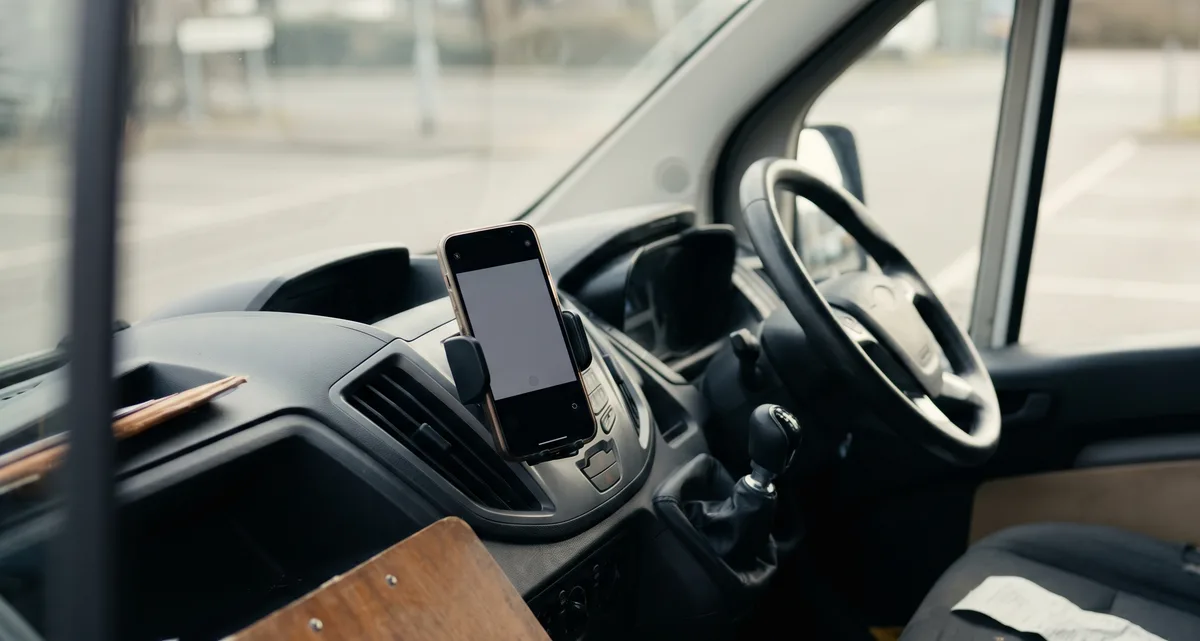 Sole trader van dashboard with a phone on a mount and a crumpled receipt on the passenger seat